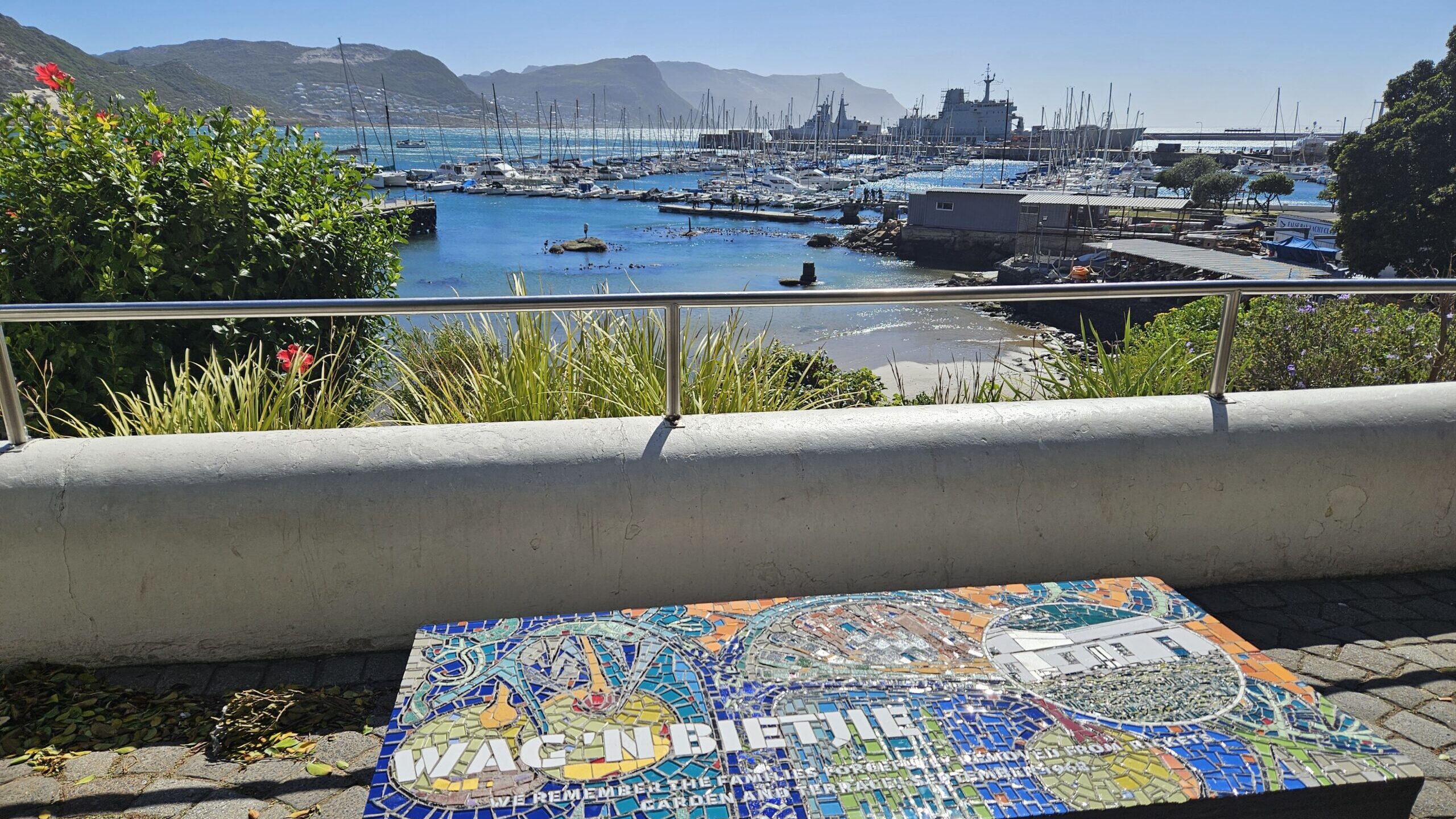 mosaic feature that says 'Wag n bietjie' with the Simonstown harbour in the background